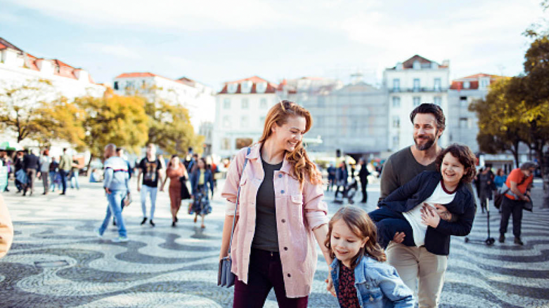 Mutter und Vater mit zwei kleinen Kindern in einer historischen Stadt auf einem offenen Platz