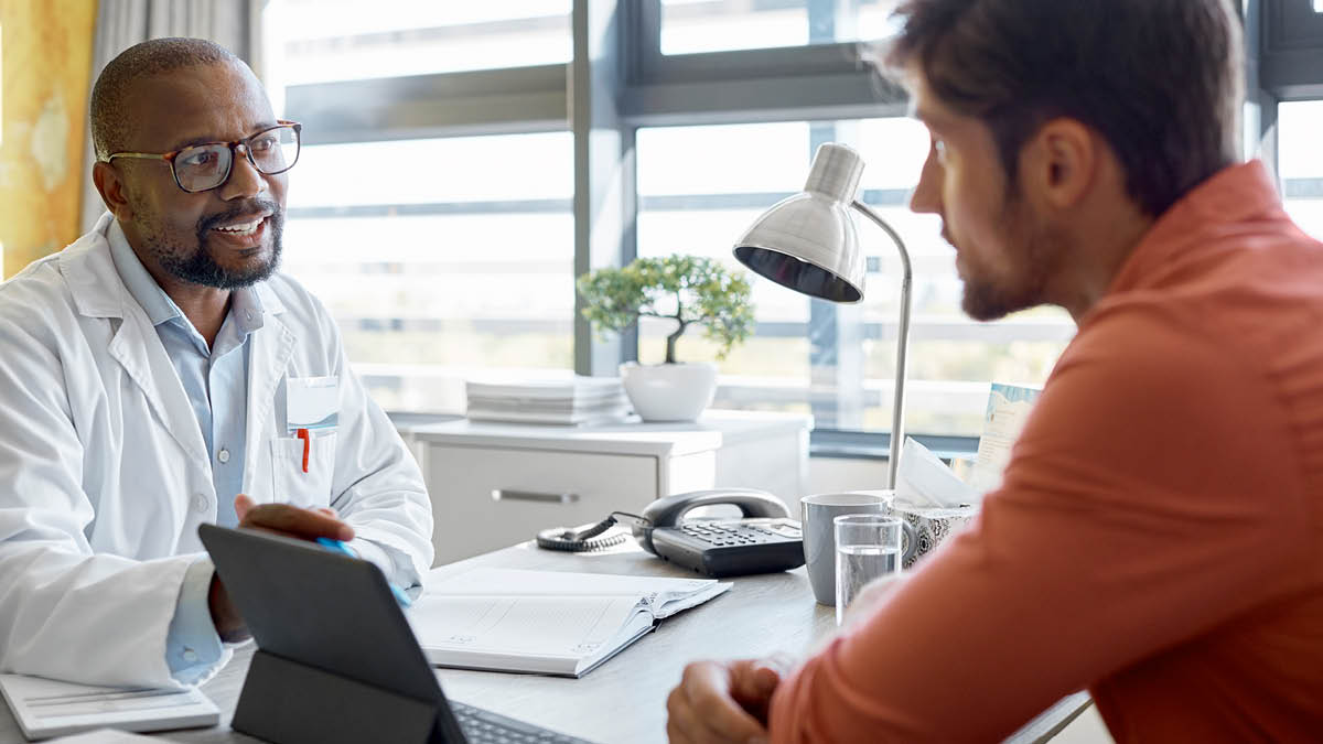 Young man in discussion with a doctor in a surgery,  they are sitting at a desk opposite each other